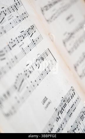 Gros plan macro de partitions de piano vieilles révélant une notation musicale nette et un papier texturé aux marges légèrement floues Banque D'Images