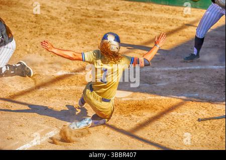 Un joueur de softball de baseball glisse dans la plaque d'accueil Banque D'Images