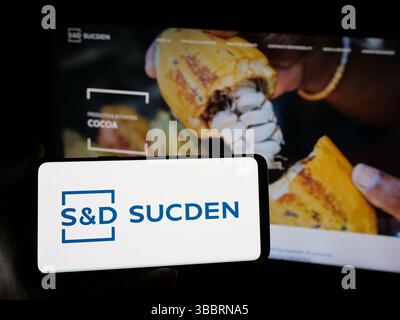 Dans cette illustration photo, une personne tient un smartphone avec le logo de la société française sucres et Denrees (Sucden) sur l'écran devant le site. Banque D'Images