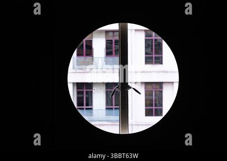 Fenêtre circulaire encadrant une façade d'immeuble moderne avec des fenêtres symétriques. Banque D'Images
