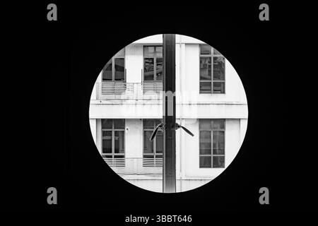 Fenêtre circulaire encadrant une façade d'immeuble moderne avec des fenêtres symétriques. Banque D'Images