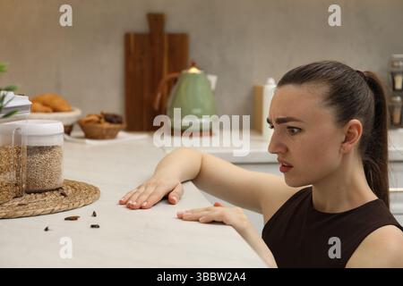 Femme regardant des cafards sur le comptoir dans la cuisine Banque D'Images