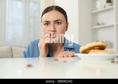 Jeune femme choquée regardant des cafards et des bretzels sur une table blanche à l'intérieur. Problème de ravageur Banque D'Images