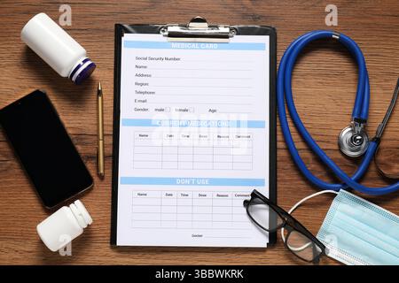Composition plate avec forme de carte médicale, smartphone, pilules et stéthoscope sur table en bois Banque D'Images