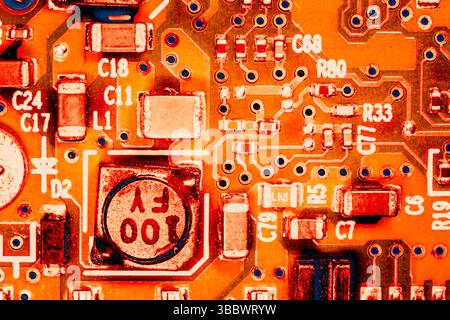toile de fond abstraite de l'ingénierie matérielle : gros plan photo d'un circuit intégré coloré en orange Banque D'Images