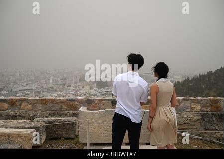 Athènes, Grèce, 16 mai 2025. Les visiteurs regardent au-dessus de la ville tandis qu'Athènes est couverte de nuages de poussière. Une épaisse couverture de poussière saharienne a balayé la capitale grecque vendredi, jetant de la brume sur la ville et suscitant des avertissements sanitaires de la part des autorités. Crédit : Dimitris Aspiotis/Alamy Live News Banque D'Images
