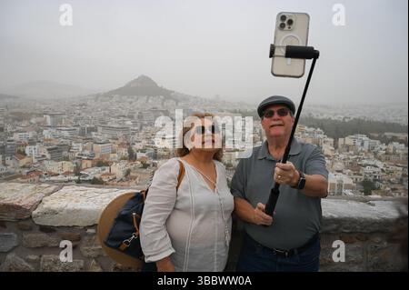 Athènes, Grèce, 16 mai 2025. Les visiteurs prennent des selfies tandis qu'Athènes est couverte de nuages de poussière. Une épaisse couverture de poussière saharienne a balayé la capitale grecque vendredi, jetant de la brume sur la ville et suscitant des avertissements sanitaires de la part des autorités. Crédit : Dimitris Aspiotis/Alamy Live News Banque D'Images