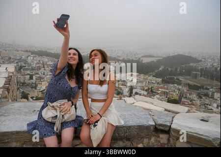 Athènes, Grèce, 16 mai 2025. Les visiteurs prennent des selfies tandis qu'Athènes est couverte de nuages de poussière. Une épaisse couverture de poussière saharienne a balayé la capitale grecque vendredi, jetant de la brume sur la ville et suscitant des avertissements sanitaires de la part des autorités. Crédit : Dimitris Aspiotis/Alamy Live News Banque D'Images