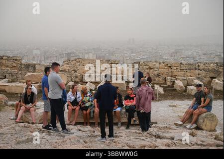 Athènes, Grèce, 16 mai 2025. Les visiteurs se rassemblent dans l'Acropole tandis qu'Athènes est couverte de nuages de poussière. Une épaisse couverture de poussière saharienne a balayé la capitale grecque vendredi, jetant de la brume sur la ville et suscitant des avertissements sanitaires de la part des autorités. Crédit : Dimitris Aspiotis/Alamy Live News Banque D'Images