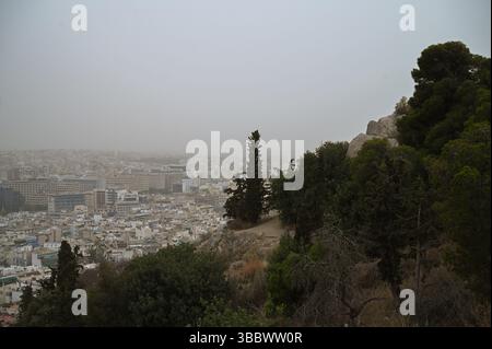 Athènes, Grèce, 16 mai 2025. Athènes est vu couvert de nuages de poussière au-dessus de la colline Philopappos. Une épaisse couverture de poussière saharienne a balayé la capitale grecque vendredi, jetant de la brume sur la ville et suscitant des avertissements sanitaires de la part des autorités. Crédit : Dimitris Aspiotis/Alamy Live News Banque D'Images