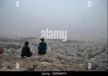 Athènes, Grèce, 16 mai 2025. Les visiteurs regardent au-dessus de la ville tandis qu'Athènes est couverte de nuages de poussière. Une épaisse couverture de poussière saharienne a balayé la capitale grecque vendredi, jetant de la brume sur la ville et suscitant des avertissements sanitaires de la part des autorités. Crédit : Dimitris Aspiotis/Alamy Banque D'Images