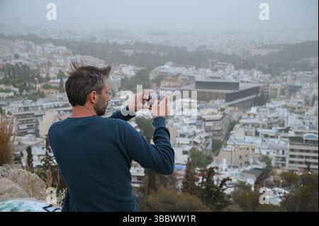 Athènes, Grèce, 16 mai 2025. Un visiteur prend des photos tandis qu'Athènes est vu couvert de nuages de poussière. Une épaisse couverture de poussière saharienne a balayé la capitale grecque vendredi, jetant de la brume sur la ville et suscitant des avertissements sanitaires de la part des autorités. Crédit : Dimitris Aspiotis/Alamy Banque D'Images