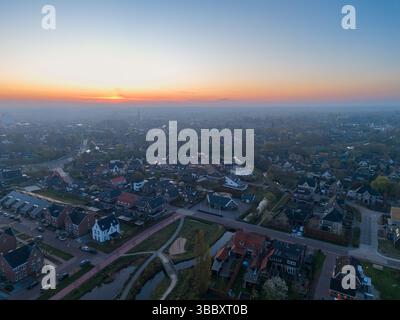 Une vue aérienne à couper le souffle de Nijkerk à l'aube, avec de charmantes maisons, des chemins sinueux, et une rivière tranquille tissant à travers le paysage. Banque D'Images