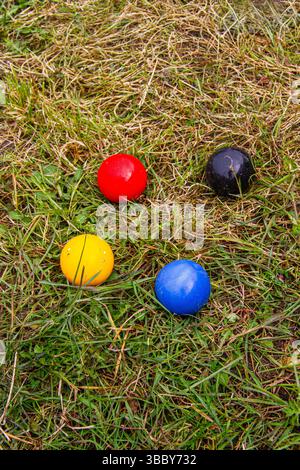 Balles de sport de croquet rouges, jaunes, bleues et noires sur fond d'herbe Banque D'Images