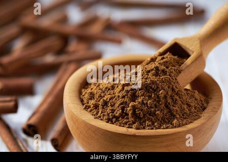 cannelle en poudre dans un bol en bois sur une table en bois blanc. Banque D'Images
