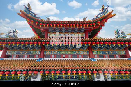 Toit orné du temple Thean Hou, Kuala Lumpur, Malaisie, orné de décorations traditionnelles chinoises, dragons, phoenixes, et de nombreuses lanternes rouges sous un ciel bleu Banque D'Images