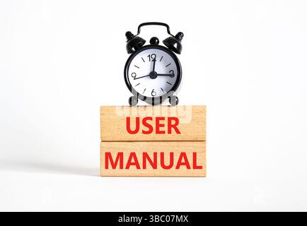 Symbole du manuel de l'utilisateur. Mots conceptuels Manuel de l'utilisateur sur blocs de bois. Beau fond blanc avec réveil. Concept du manuel d'utilisation et de l'entreprise. Copier sp Banque D'Images