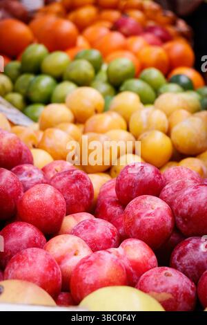Image abstraite gros plan assorti de fruits frais, y compris des oranges, des citrons verts, des prunes et des pommes, exposés dans un étal de marché animé de tenerife en espagne Banque D'Images