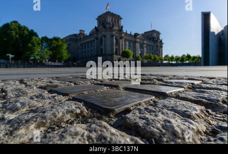 Les pierres commémoratives de Stolpersteine à Berlin commémorent les victimes nazies, avec le Reichstag allemand en arrière-plan flou. Pierres de trébuchement. Banque D'Images