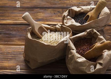 Close up de sacs de papier blanc, rouge et noir les graines de quinoa avec scooops Banque D'Images