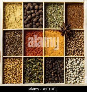 Boîte en bois divisée en cellules pour le stockage des herbes et des épices. Assortiment de condiments et d'épices dans des cellules rectangulaires. Composition abstraite, vue de dessus, Banque D'Images