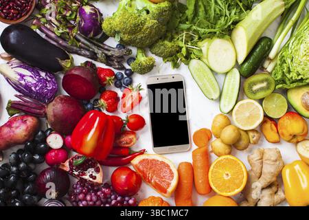 Livraison de fruits et légumes frais biologiques. Produits agricoles, smartphone avec nourriture végétalienne arc-en-ciel, vue du dessus Banque D'Images