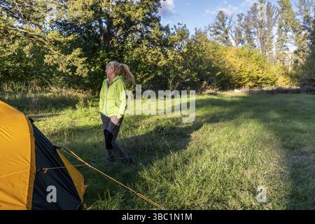Femme blonde ensoleillée riant pendant l'aventure en plein air dans un beau paysage Banque D'Images