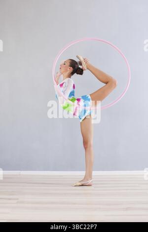 Portrait de jeune fille gymnaste souple que faire exploit acrobatique avec cerceau rose Banque D'Images