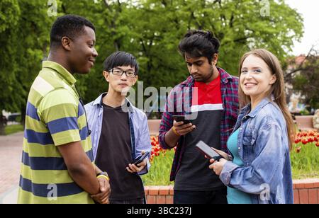 Un groupe d'étudiants divers communique facilement après des conférences universitaires. Établir des liens étroits entre les jeunes de différentes races et nationalités Banque D'Images