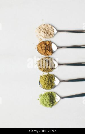 Cuillères avec différentes poudres de super-aliments colorées sur une table en marbre blanc Banque D'Images