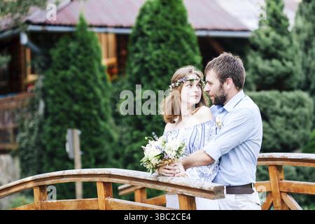 Couple de mariage éclectique extérieur.La mariée et le marié se tiennent sur le pont Banque D'Images