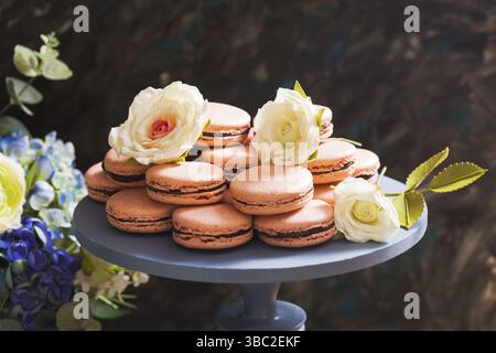 Macarons sur le stand en bois, décorés de fleurs de sucre Banque D'Images