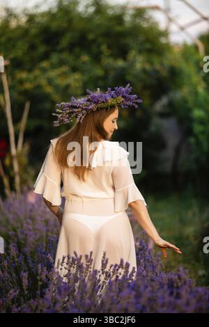 Femme en couronne de lavande et robe de whitre sur le champ de lavande. Fille collectionne la lavande Banque D'Images