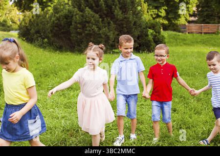 Groupe d'enfants tenant les mains et jouant en plein air. Joyeuses vacances d'été Banque D'Images
