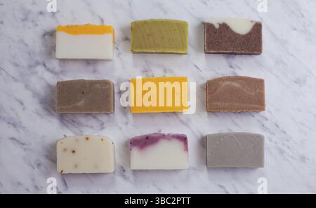 Vue de dessus plat de neuf différents morceaux de savon biologique fait à la main, posé sur une surface en marbre. Concept de cosmétiques écologiques Banque D'Images