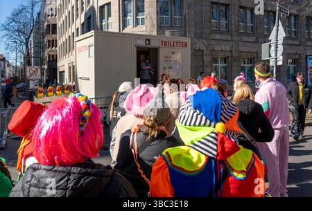 Défilé du carnaval Rose Monday à Düsseldorf, des gens en tenue de fantaisie se tenaient devant des toilettes portables. Banque D'Images
