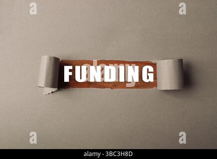 Le mot financement est écrit sur un morceau de papier déchiré en deux. Le papier est marron et le mot est blanc Banque D'Images