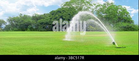 Système d'irrigation de pelouse avec une bonne pression d'eau sur un terrain de golf vert et frais sur fond d'arbres sous le soleil brillant pendant la journée. A lus Banque D'Images