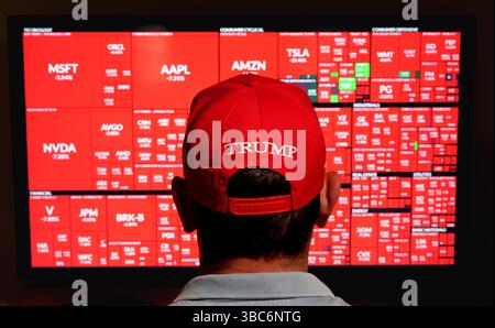 Homme portant un chapeau rouge Trump regardant la carte de chaleur du marché boursier avec de graves pertes dans le secteur S&P 500 lorsque Trump a provoqué des retards. Stafford, United King Banque D'Images