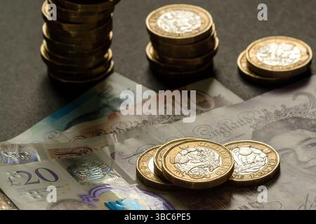 Piles de pièces britanniques d'une livre placées sur des billets de cinq, dix et vingt livres, symbolisant l'épargne, le budget et la richesse au Royaume-Uni, Stafford, Unite Banque D'Images
