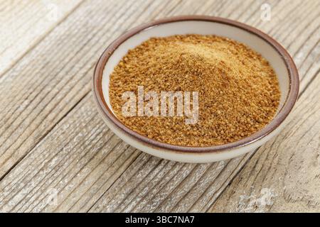 Petit bol en céramique de sucre de palme de noix de coco non raffiné sur fond de bois grunge peint en blanc Banque D'Images