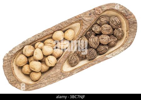 Et black les noix dans un bac en bois de manguier split avec écorce bords, isolé sur blanc, vue d'en haut Banque D'Images