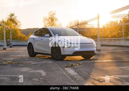 Une voiture blanche dans un parking avec une toile de fond automnale et coucher de soleil, Tesla nouveau modèle y Juniper, Nagold, Allemagne, Europe Banque D'Images