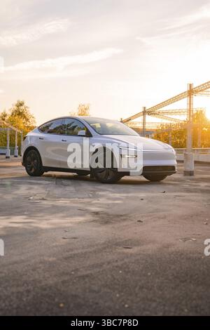 Une voiture blanche dans un parking urbain au lever du soleil, Tesla New Model y Juniper, Nagold, Allemagne, Europe Banque D'Images