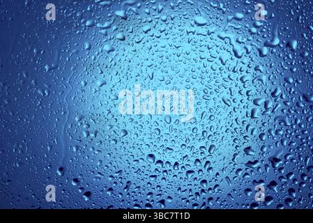 Gouttes d'eau sur verre sur fond bleu Banque D'Images