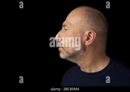 homme chauve de 60 ans avec une barbe - un portrait de profil sur un fond noir Banque D'Images
