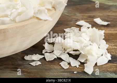 Flocons de noix de coco râpée sur une table en bois rustique et dans un bol Banque D'Images