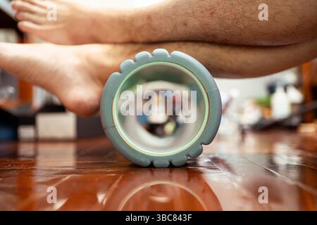 Utiliser un rouleau en mousse pour étirer le muscle du mollet et soulager la douleur au talon. Les exercices de rouleau de mousse sont utiles pour la récupération d'un coureur. Banque D'Images