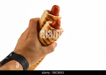Une main saisit solidement deux hot dogs grillés enveloppés dans du pain grillé. La collation simple se distingue sur un fond Uni, mettant en vedette un repas savoureux o Banque D'Images