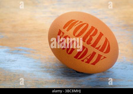 World Egg Day - texte pochoir sur un oeuf contre bois peint grunge Banque D'Images